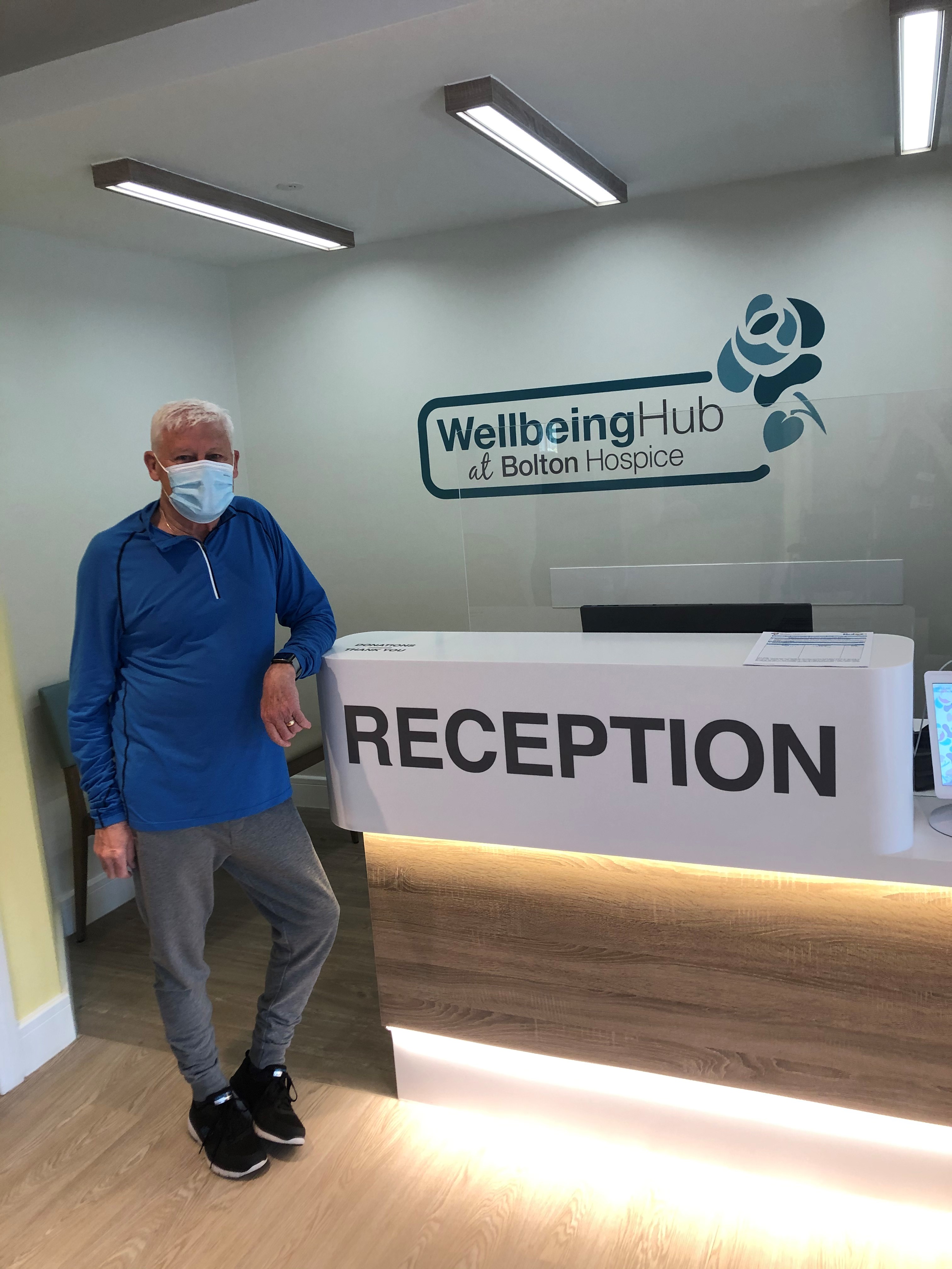Patient stood at the reception desk of the Wellbeing Hub