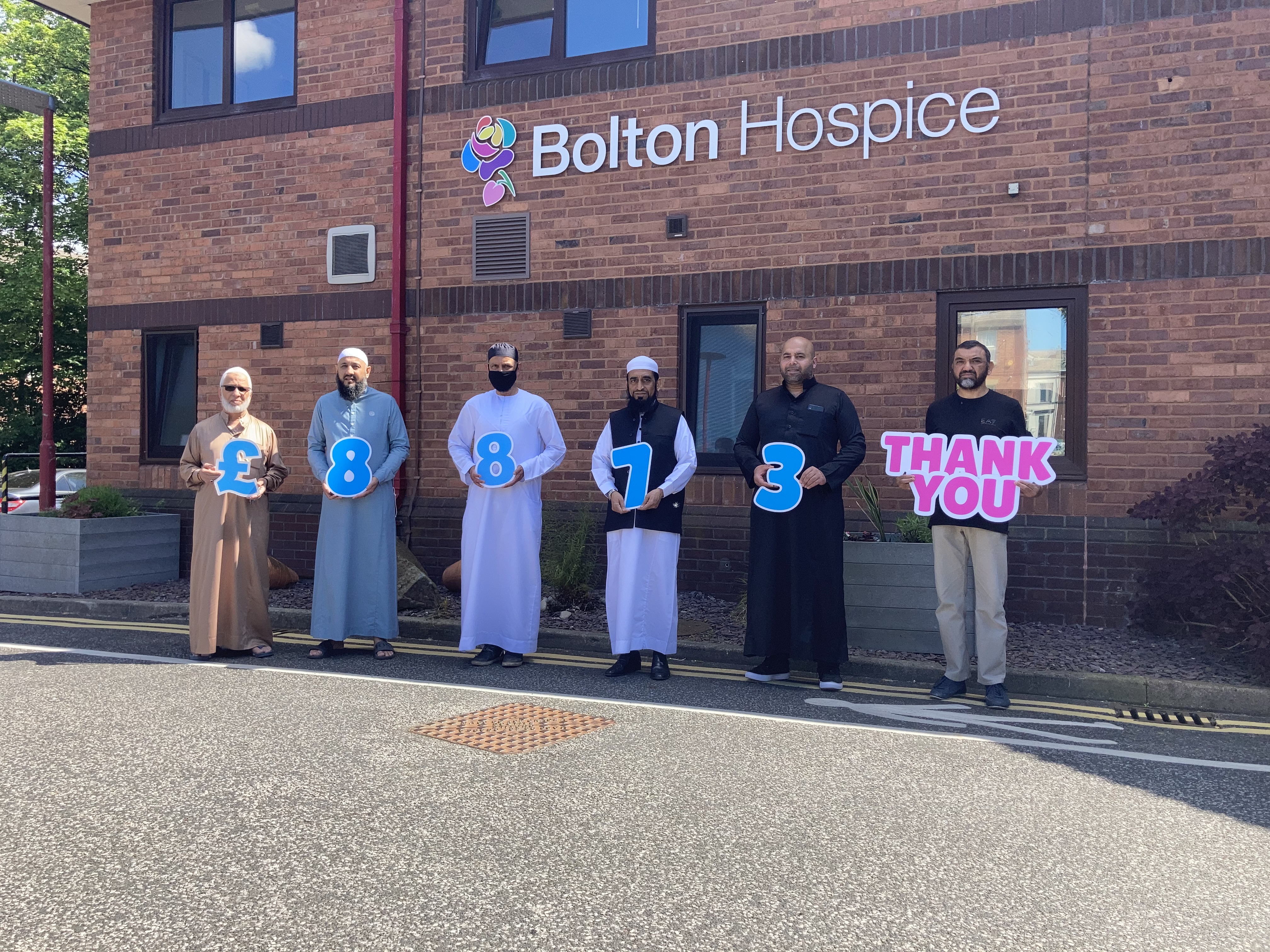 Mosque representatives holding up sign with total funds raised